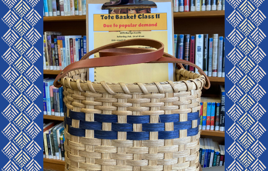 A woven basket sits in front of a shelf of books. Inside the basket is a clipboard advertising a basket making class on Saturday, February 24th at 10am.